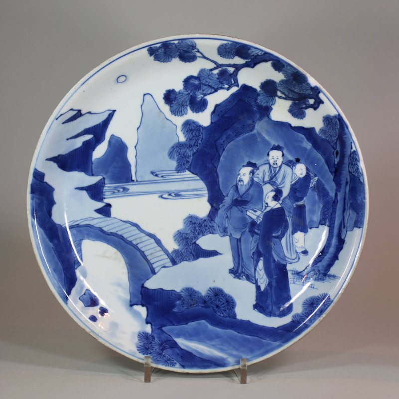 Chinese blue and white dish, Kangxi (1662-1722), decorated with three scholars and an attendant in a riverscape by a bridge beneath a pine tree, diameter: 10 5/8 in. (26.8 cm.) Provenance: Purchased in 1913 by Veroudart in Beijing, the French consul in Canton.