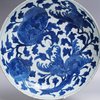 W935 A large blue and white saucer dish, Kangxi (1662-1722), decorated in underglaze cobalt blue with large fruiting boughs citrus and buddha's hand citron amongst foliage and small flying insects, the rev